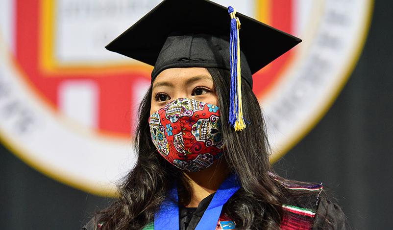 Alma standing in front of the university crest at her graduation ceremony